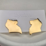 Gold earrings on a white card held in a hand with a blurred background