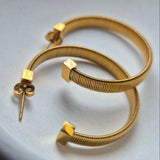 Gold hoop earrings on a white surface