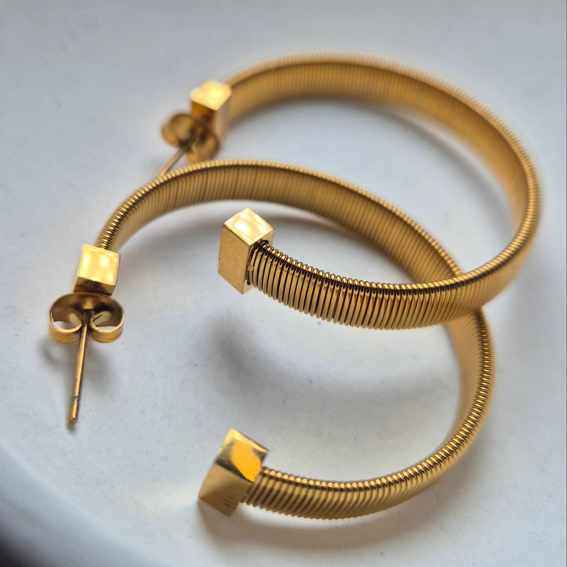 Gold hoop earrings on a white surface