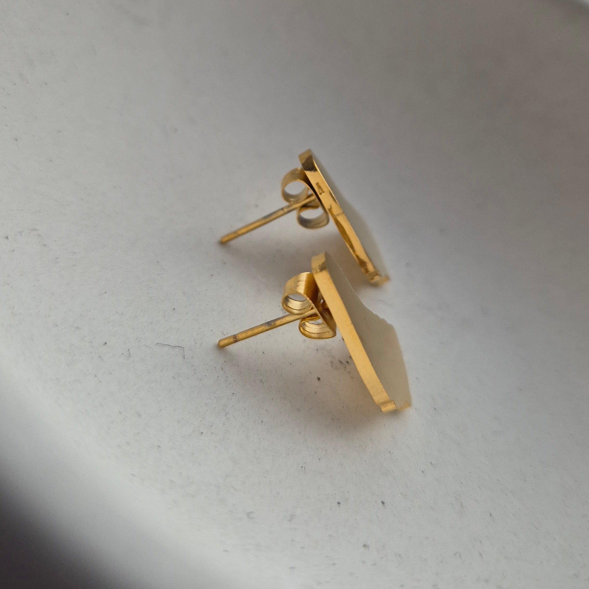 Gold earring on a white surface with a blurred background