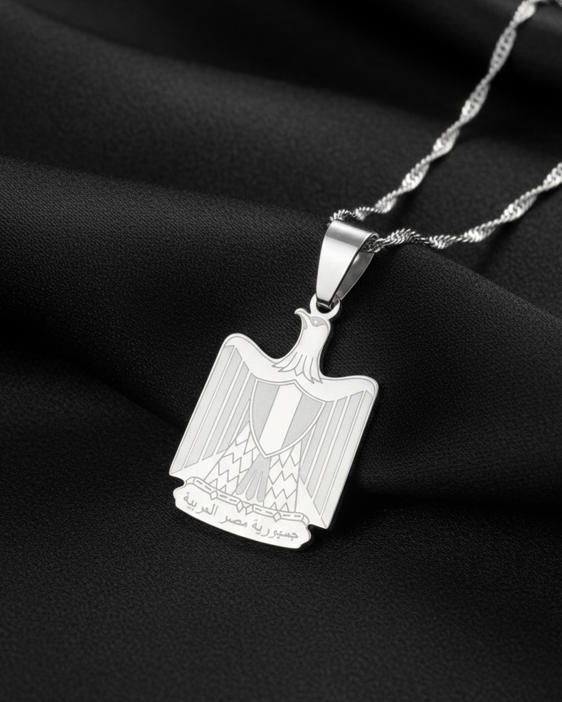 Silver pendant with a detailed design on a black fabric background