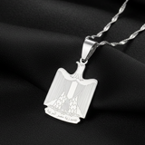 Silver pendant with a detailed design on a black fabric background