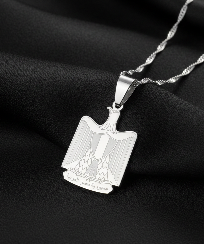 Silver pendant with a detailed design on a black fabric background