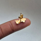 Gold Guyana map-shaped earring on a finger against a neutral background