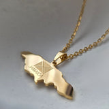 Gold necklace with a map of Jamaica pendant on a light gray background