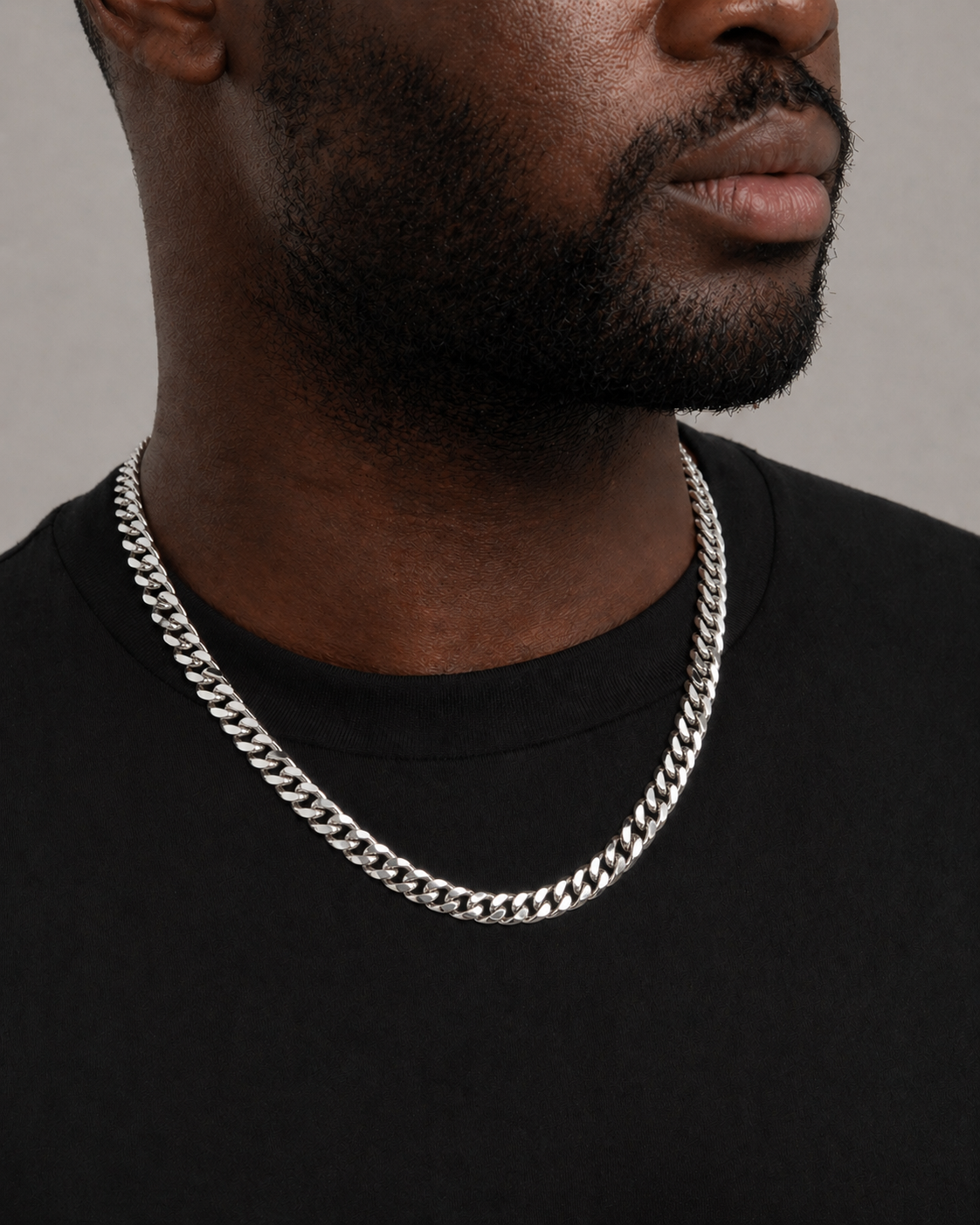 Man wearing a silver chain necklace against a neutral background