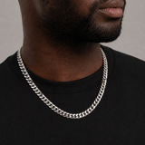 Man wearing a silver chain necklace against a neutral background