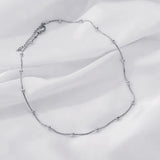 Silver necklace on a white fabric background