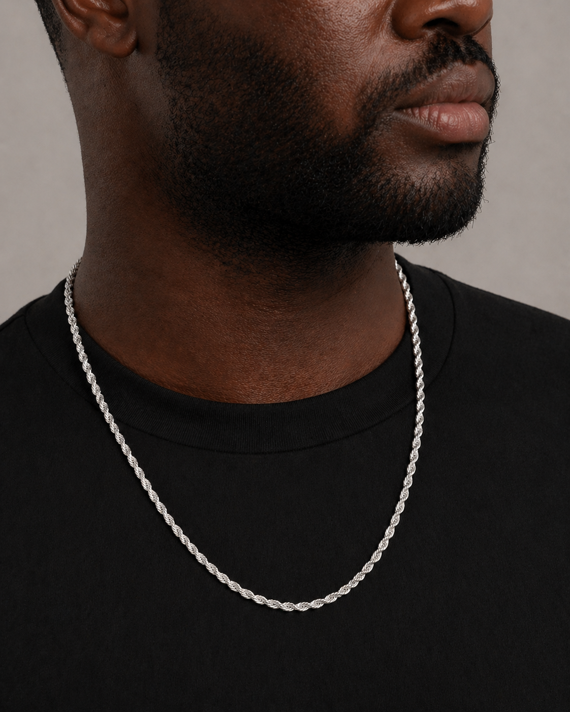 Man wearing a silver chain necklace against a neutral background