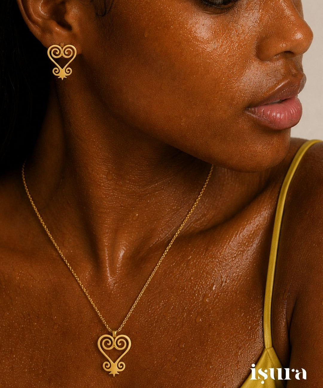 Close-up of a person wearing a gold earring and necklace with 'isura' branding.