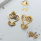 Gold heart-shaped earrings on a light background