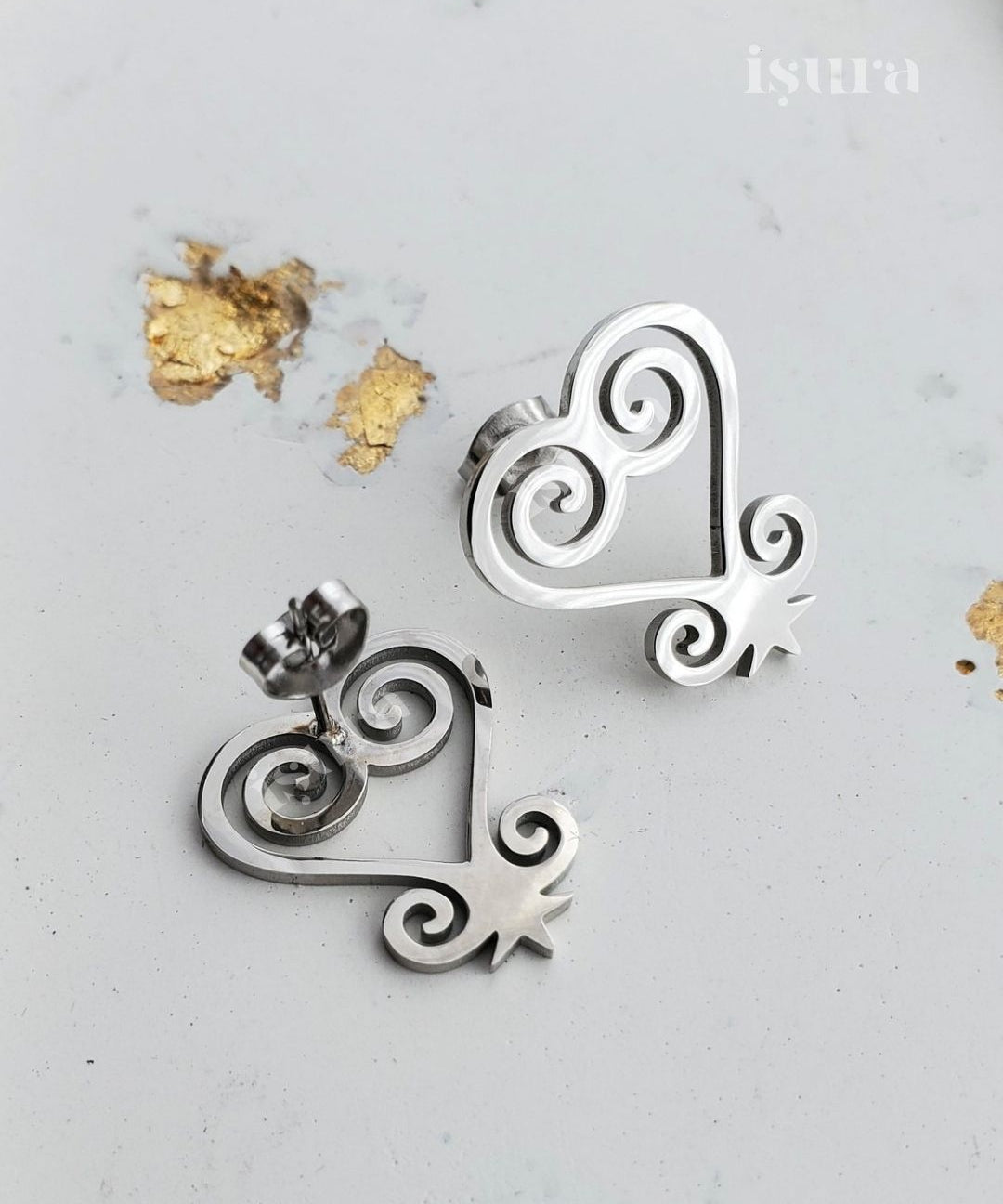 Silver earrings with intricate designs on a light gray background