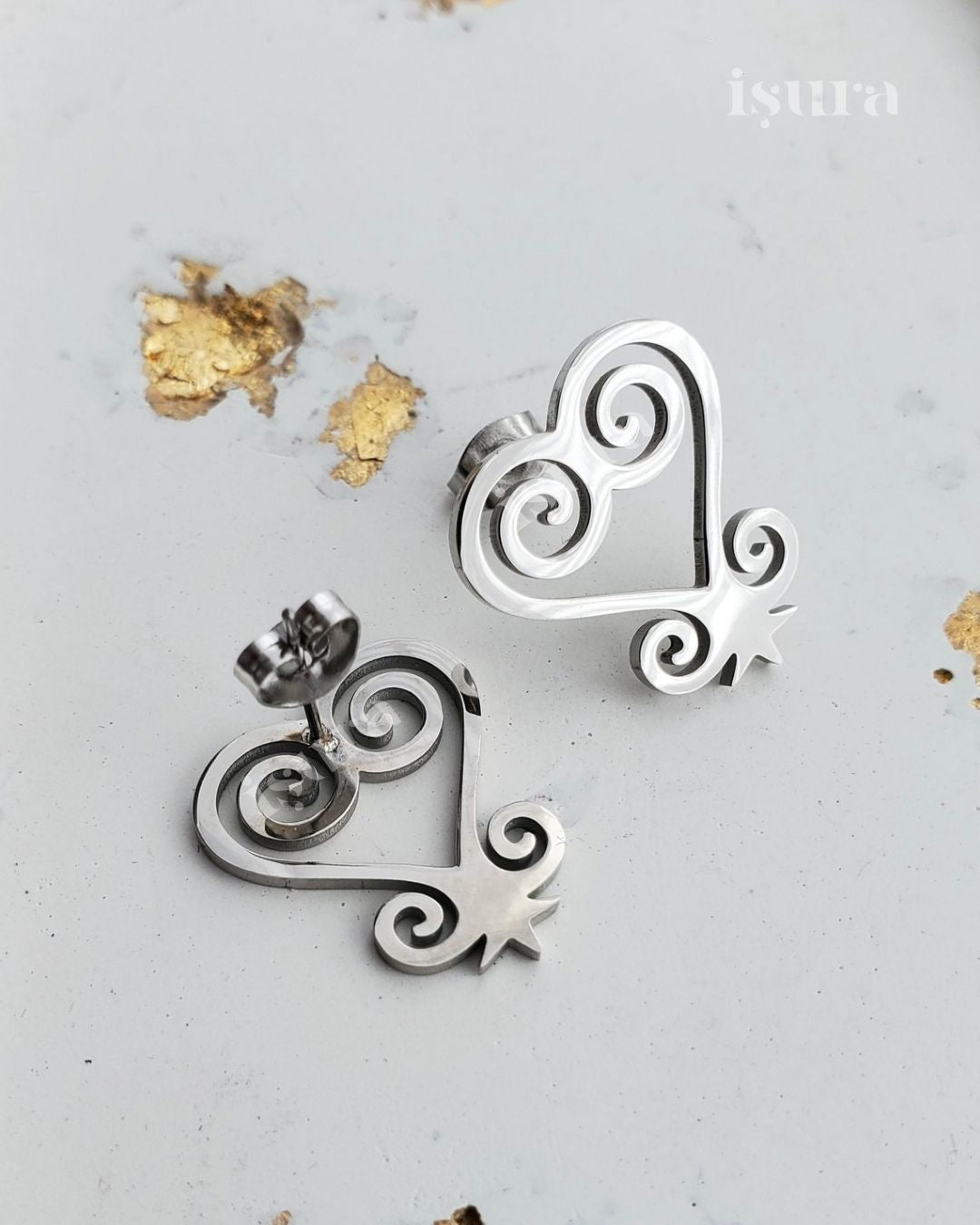 Silver earrings with intricate designs on a light gray background