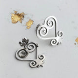 Silver earrings with intricate designs on a light gray background