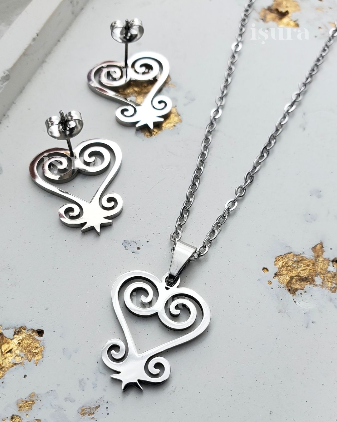 Silver heart-shaped jewelry set with necklace and earrings on a light background