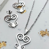 Silver heart-shaped jewelry set with necklace and earrings on a light background