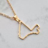 Gold necklace with a unique pendant on a light gray background