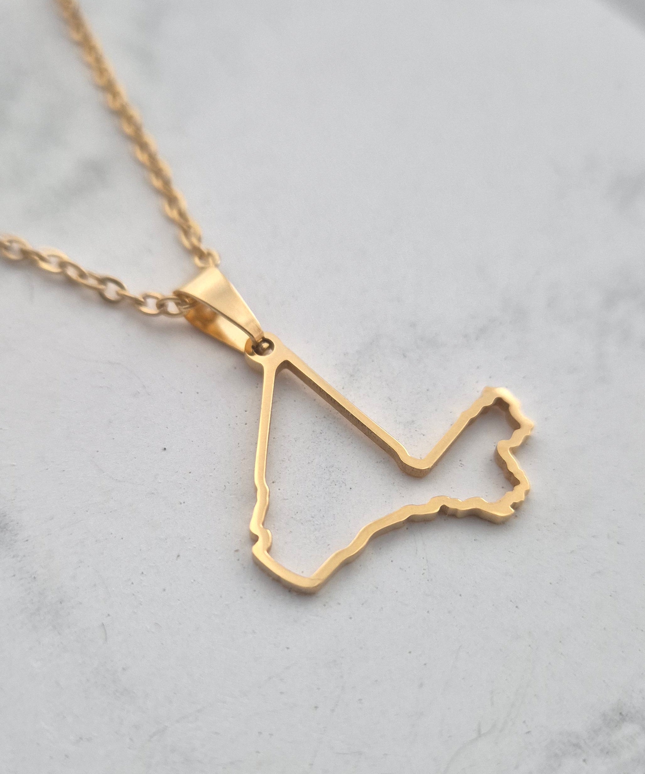 Gold necklace with a unique pendant on a light gray background
