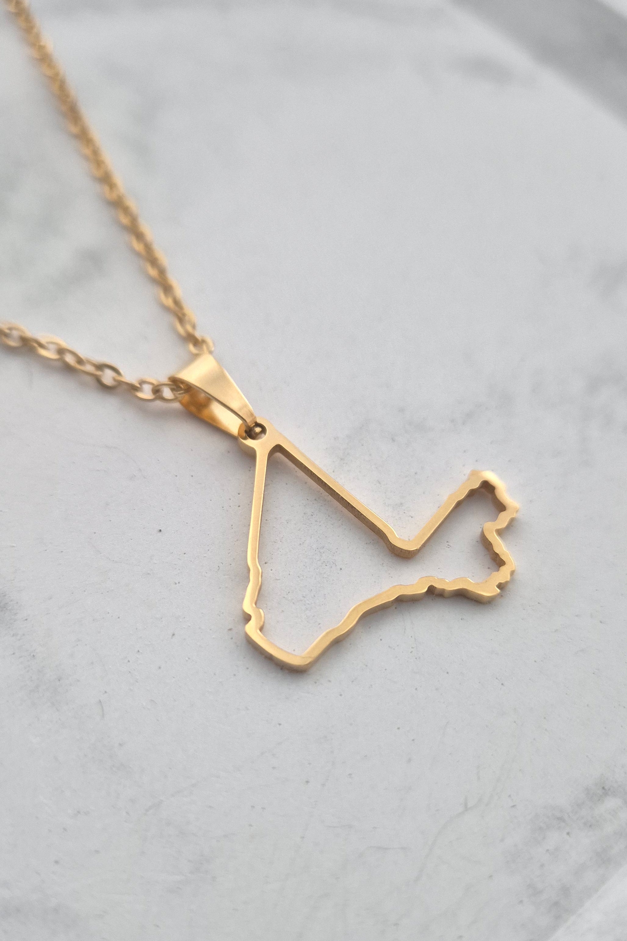 Gold necklace with a unique pendant on a light gray background